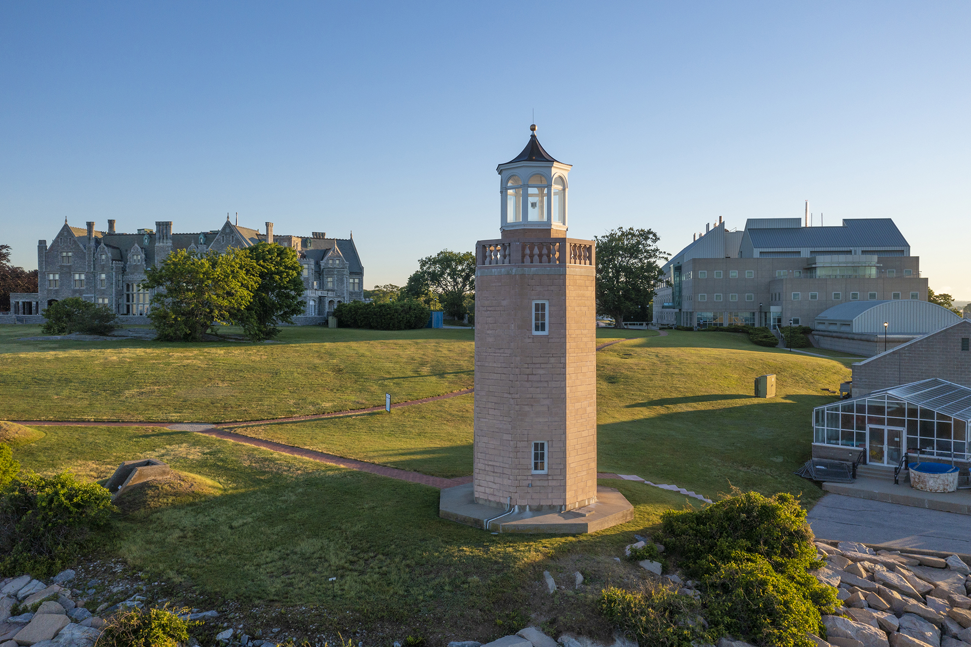 A drone view of the Avery Point lighthouse with Branford House in the background to the left